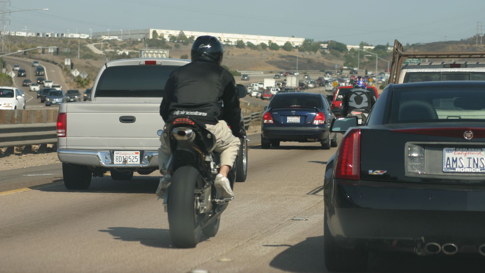 A motorcycle riding between two lanes of slow freeway traffic