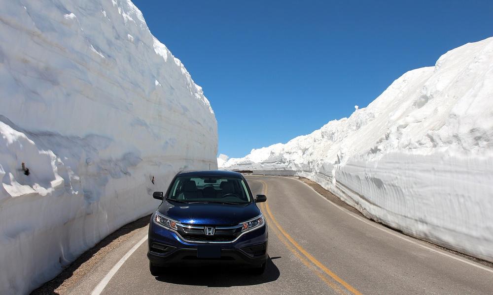 A car between plowed snow walls on the Beartooth Highway after the spring plow