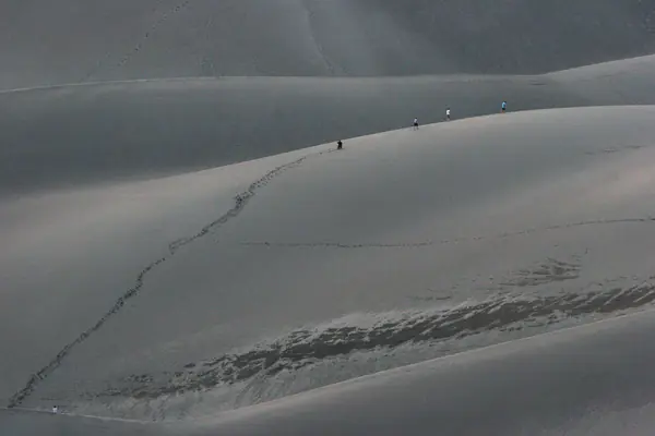 Hikers climb the dunes