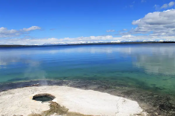 A geyser steams beside Yellowstone Lake